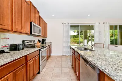 a large kitchen with wooden cabinets and granite counter tops at Charming Home Near Disney With Private Pool And Waterpark & Resort Access At Encore Resorts Reunion - 7389Mr in Kissimmee