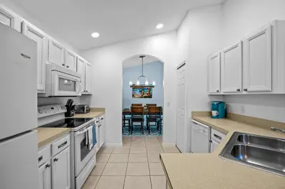 a kitchen with white cabinets and a dining room at Near Disney, Recently Renovated, Clubhouse in Kissimmee