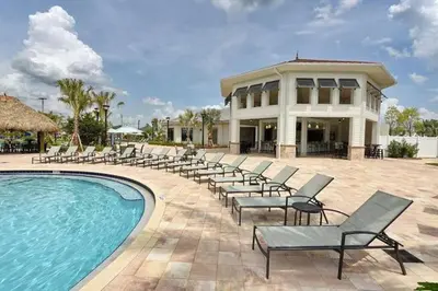 a resort with a pool and chairs and a building at Excellent Resort Free/ Makin Memories / 4 Beds in Kissimmee