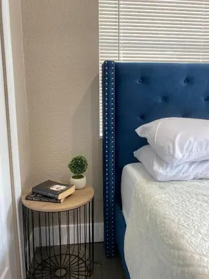 a bed with a blue headboard and a table with a plant at Bella Breeze in Sanford