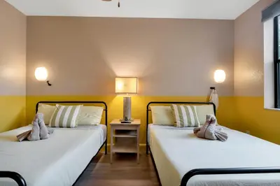 two beds in a room with yellow walls at Designer 3BR/2BA Corner Suite - Disney & Universal in Orlando