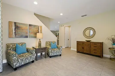 a living room with two chairs and a table and a mirror at Luxurious Encore Villa 10 Min Disney Inc/Waterpark in Orlando
