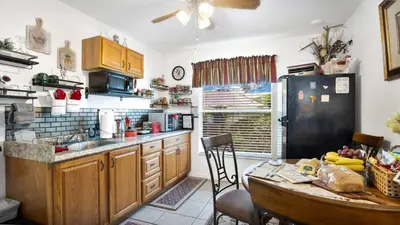 a kitchen with a table and a black refrigerator at La Maison de Lorbu - Apartment in Orlando