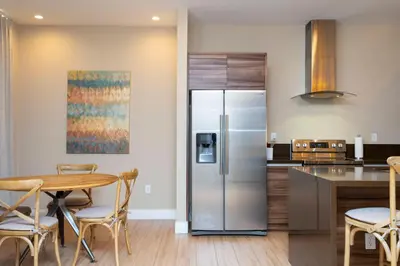 a kitchen with a stainless steel refrigerator and a table at 4 Suites - 5 min from Disney - w Jacuzzi 7557 in Orlando