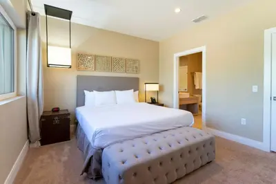 a bedroom with a large white bed and a stool at 4 Suites - 5 min from Disney - w Jacuzzi 7557 in Orlando