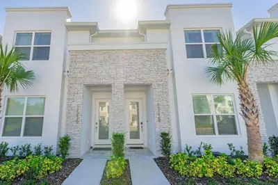 a white house with palm trees in front of it at Private Pool Villa Family Retreat Near Disney World in Orlando