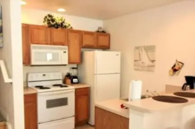 a kitchen with a white refrigerator and wooden cabinets at Family Friendly 3BR near Disney in Kissimmee