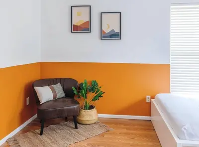 a chair in a bedroom with an orange wall at Orlando Boho Villa in Kissimmee