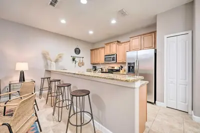 a kitchen with bar stools and a kitchen with a refrigerator at Private Pool and Lanai Resort Townhome in Kissimmee in Kissimmee