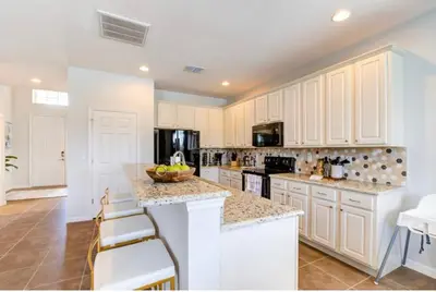 a kitchen with white cabinets and a bowl of fruit on a counter at 6BR Resort Villa Near Disney Private Pool 2584 in Kissimmee