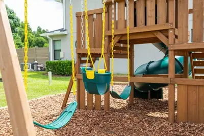 a playground with a green slide and swings at Relax water view with Hammock near Disney 4736 in Kissimmee