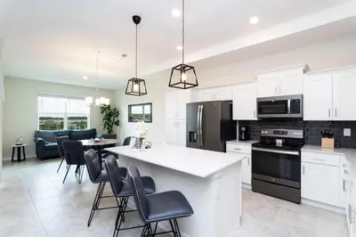 a kitchen with white cabinets and a kitchen island with chairs at Modern Condo with Lake View Near Disney 3151 in Kissimmee