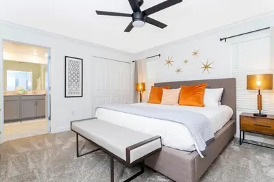 a bedroom with a large white bed with orange pillows at free resort access, private pool near disney 2966 in Kissimmee