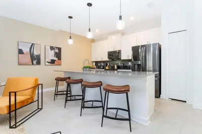 a kitchen with a bar with stools and a refrigerator at Modern Clean home Private Pool close Disney 2968 in Kissimmee