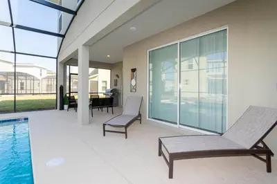 a patio with a pool and chairs and a table at Resort-Style Private Pool & Spa Modern 2920 in Kissimmee