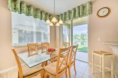 a dining room with a table and chairs and a clock at Kissimmee Getaway about 4 Mi to Walt Disney World in Kissimmee
