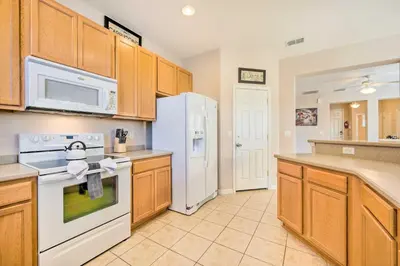 a kitchen with wooden cabinets and a white refrigerator at Kissimmee Getaway about 4 Mi to Walt Disney World in Kissimmee