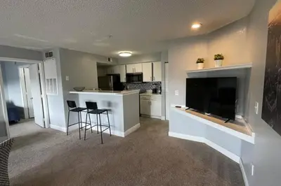 a living room with a large television and a kitchen at very Nice 2/2 apartment , close to disney in Kissimmee