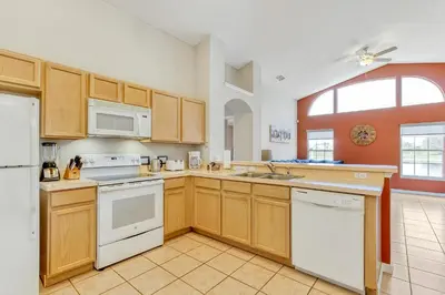 a large kitchen with wooden cabinets and white appliances at Star Lake Oasis - 4 bed family pool home in Orlando