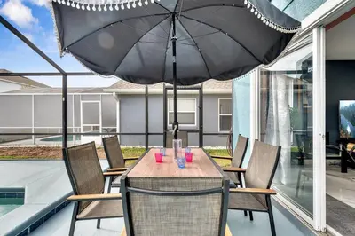 a table and chairs with an umbrella on a patio at South Facing Pool, Close to Attractions, Remodeled in Kissimmee
