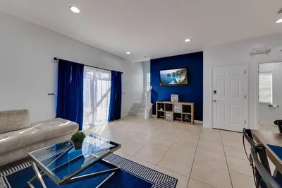 a living room with a glass table and blue walls at Welcome to Villa Azul, your home away from home! in Kissimmee