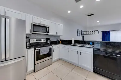 a kitchen with white cabinets and stainless steel appliances at Welcome to Villa Azul, your home away from home! in Kissimmee