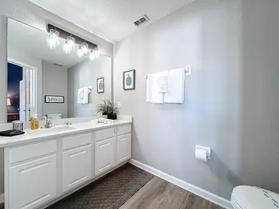 a white bathroom with a sink and a mirror at Private Pool Disney Townhome - Walk to Water Park in Orlando