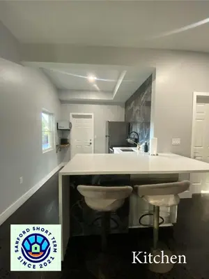 a kitchen with a white counter and two stools at The Front Porch in Sanford
