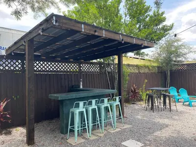 a wooden pergola with stools and a table and chairs at The Front Porch in Sanford