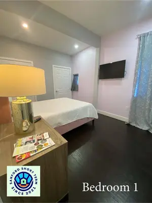 a bedroom with a bed and a table with a lamp at The Front Porch in Sanford
