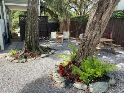 a garden with two trees and a bench and flowers at The Jazz Loft in Sanford