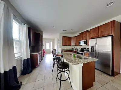 a kitchen with a counter with chairs and a refrigerator at 561 - 8BD Villa - Private PoolSpa by Disney in Orlando