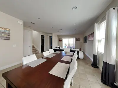 a large dining room with a long table and white chairs at 561 - 8BD Villa - Private PoolSpa by Disney in Orlando
