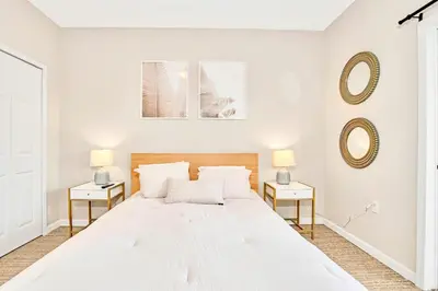 a white bedroom with a large white bed and two tables at Stylish 3BR Suite with Swimming Pool - Near Disney in Orlando