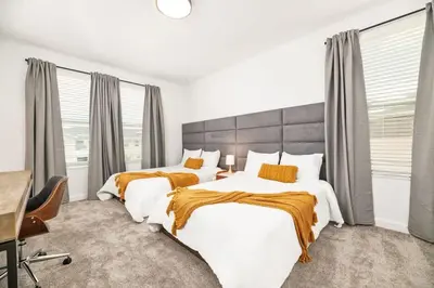 a bedroom with two beds and a desk and windows at Luxury home, private pool, themed bedrooms, prime location in Kissimmee