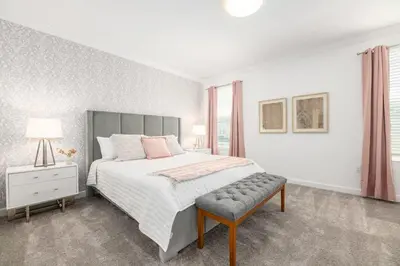 a white bedroom with a large bed and a chair at Luxury home, private pool, themed bedrooms, prime location in Kissimmee
