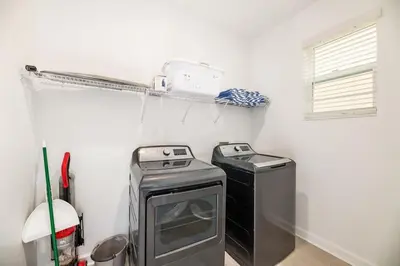 a laundry room with a stove and a washer and dryer at Luxury home, private pool, themed bedrooms, prime location in Kissimmee