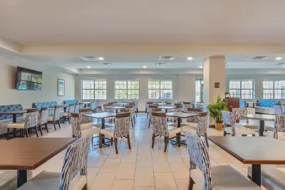 a dining room with tables and chairs and windows at Pestana Orlando Suites - Lake Buena Vista in Orlando