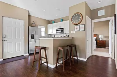 a kitchen with a bar with stools and a clock on the wall at Welcoming 4 BR Sleeps 10 Guests WL2901 in Kissimmee
