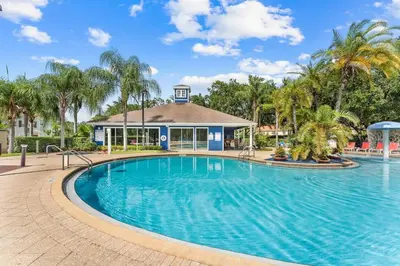 a swimming pool in front of a building with palm trees at Welcoming 4 BR Sleeps 10 Guests WL2901 in Kissimmee