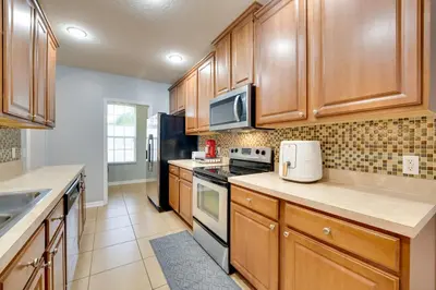 a kitchen with wooden cabinets and a stove top oven at 15 Mi to Disney Kissimmee Townhome with Patio in Kissimmee