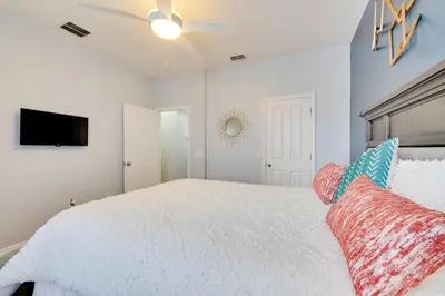 a bedroom with a white bed and a flat screen tv at 15 Mi to Disney Kissimmee Townhome with Patio in Kissimmee