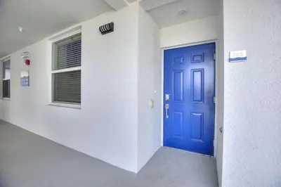 an empty hallway with a blue door and a window at Resort Life at Storey Lake by Shine Villas, #702 apts in Kissimmee
