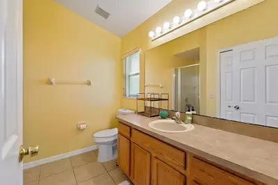 a bathroom with a sink and a toilet and a mirror at Gilded Parasol by Shine Villas Remington Golf #410 home in Kissimmee