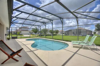a swimming pool under a glass roof with chairs and a patio at Gilded Parasol by Shine Villas Remington Golf #410 home in Kissimmee