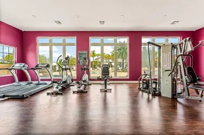 a gym with cardio equipment in a room with pink walls at Lucky Find Lucaya Resort by Shine Villas #713 townhouse in Kissimmee