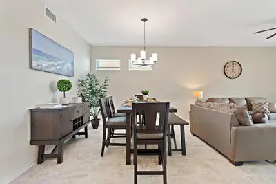 a dining room and living room with a table and a couch at Triple Header Storey Lake by Shine Villas apts in Kissimmee