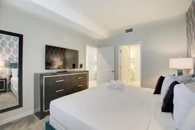 a bedroom with a white bed and a flat screen tv at Decadent Penguin - Storey Lake by Shine Villas 704 apts in Kissimmee