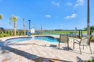 a swimming pool with two chairs and a table at Decadent Penguin - Storey Lake by Shine Villas 704 apts in Kissimmee