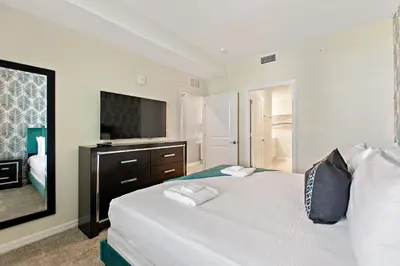 a bedroom with a large bed with a television at Decadent Penguin - Storey Lake by Shine Villas 704 apts in Kissimmee